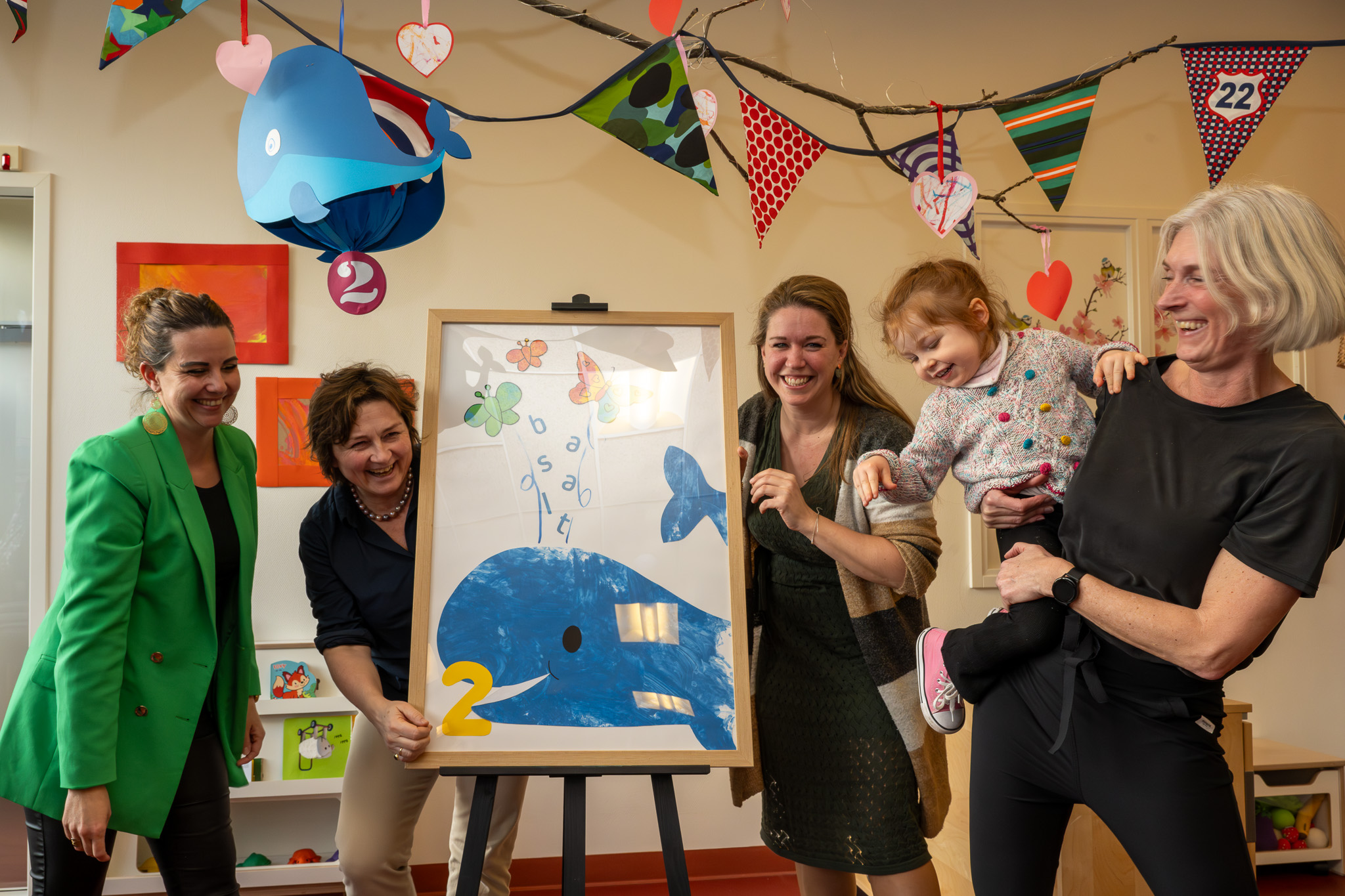 Izabella (3 jaar) onthult met pedagogisch medewerker en drie directeur bestuurders van Kinderopvang 2Samen, Kinderopvang Kombino en revalidatiecentrum Basalt een zelfgemaakt kunstwerk. Hiermee wordt het nieuwe kinderdagverblijf 2Walvissen geopend.