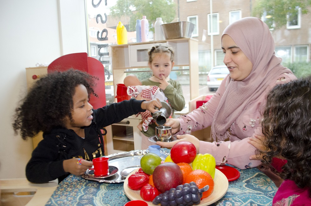 medewerker met kinderen aan tafel bij bso 2onder elkaar in spoorwijk den haag