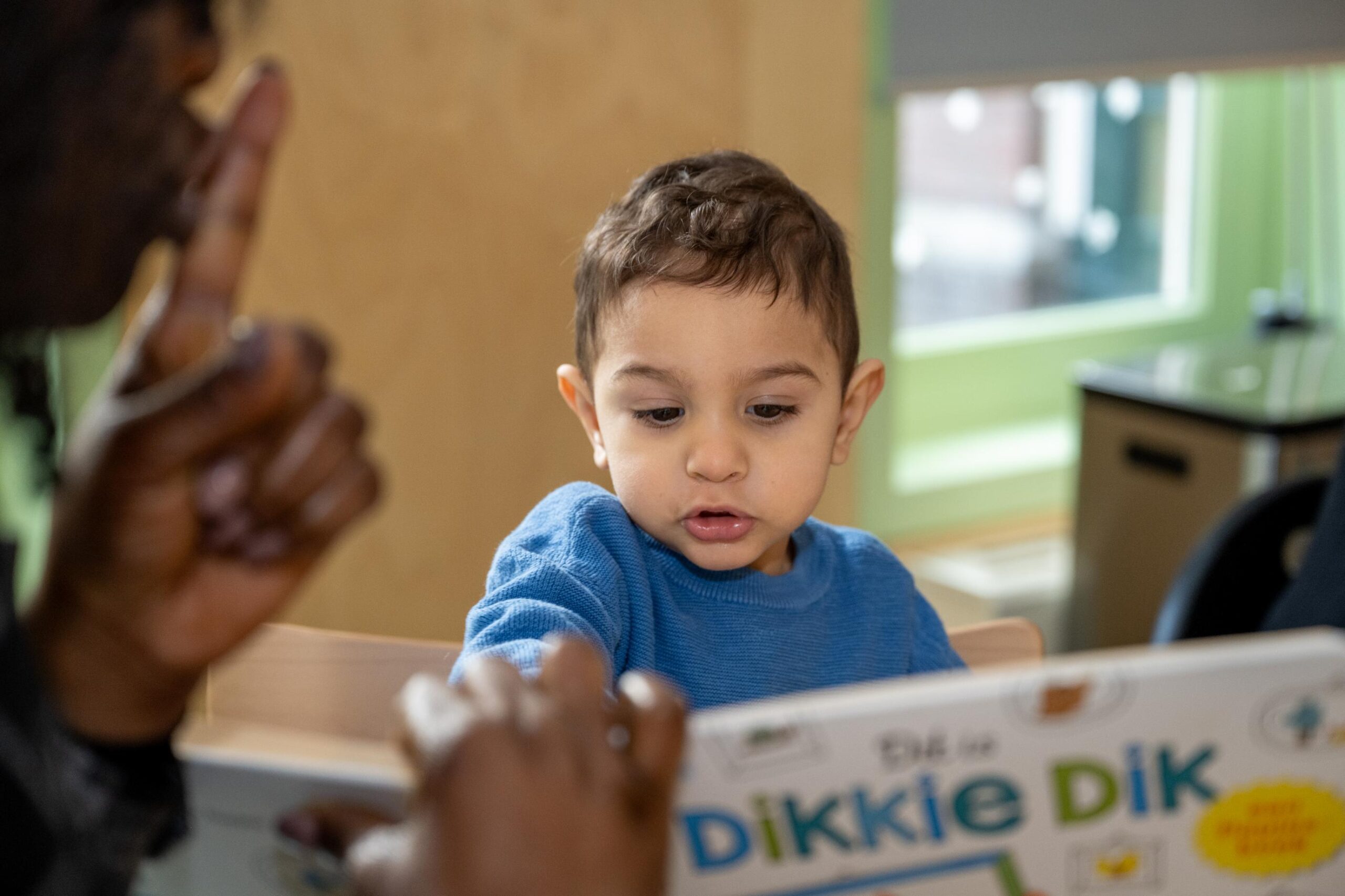 kind en medewerker lezen boekje bij voorschoolse educatie 2koninkjes in het centrum van den haag