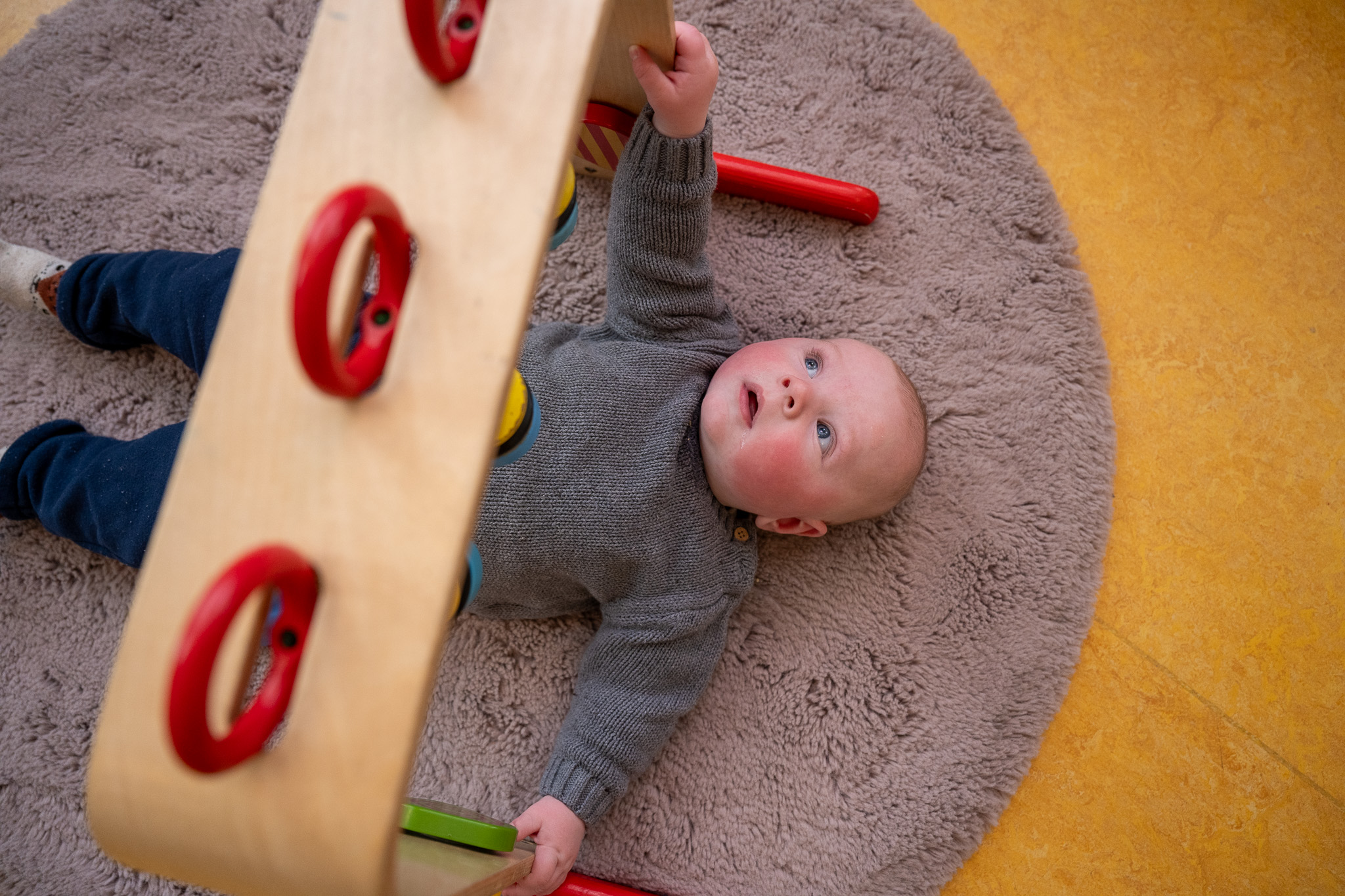 Baby op een speelkleed met speelgoed boven zich bij kdv 2Zonnebloemen in Regentteskwartier