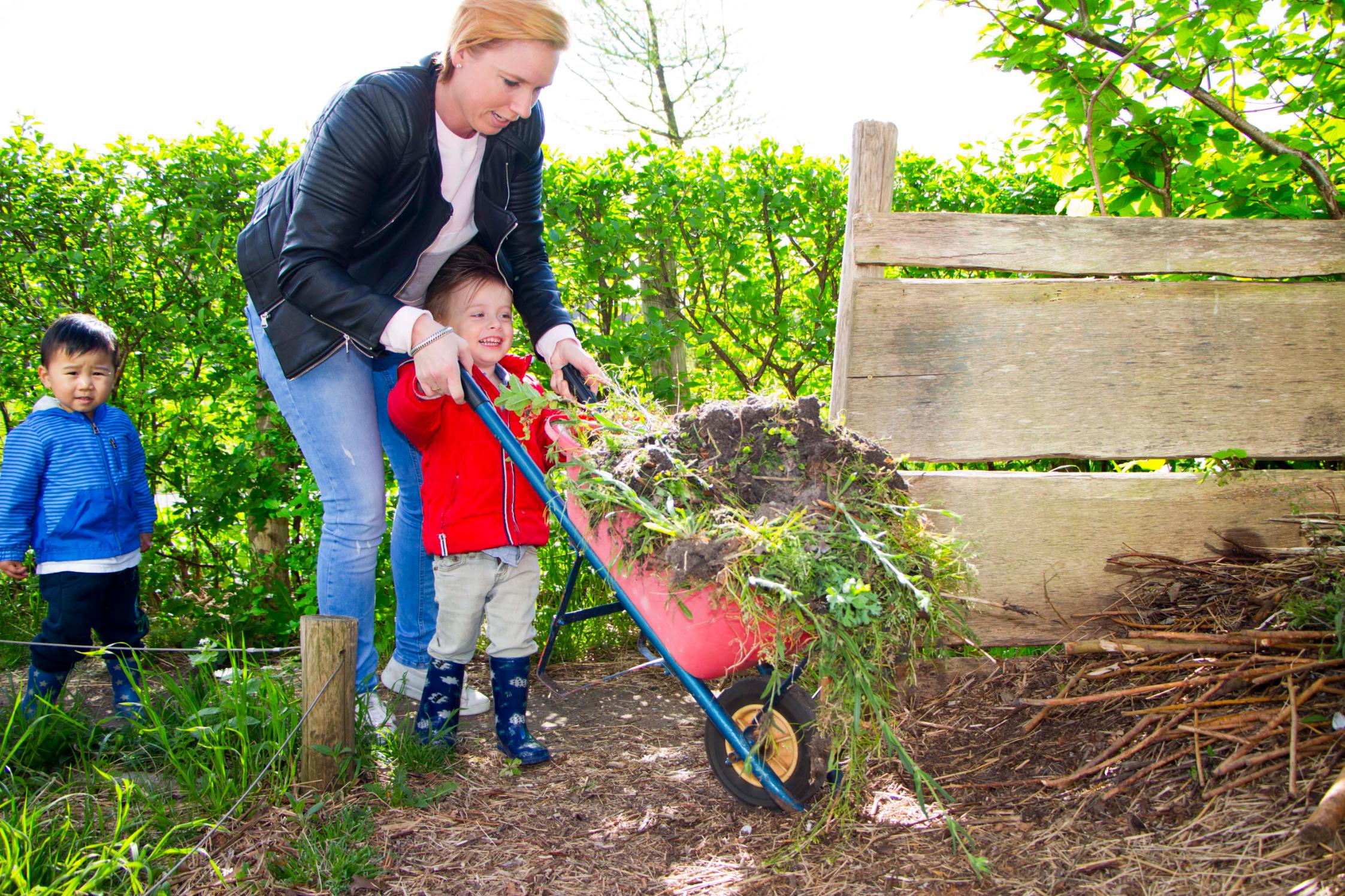 medewerker en kind met kruiwagen Moestuin kinderdagverblijf 2Zwanen Ypenburg Den Haag Kinderopvang 2Samen