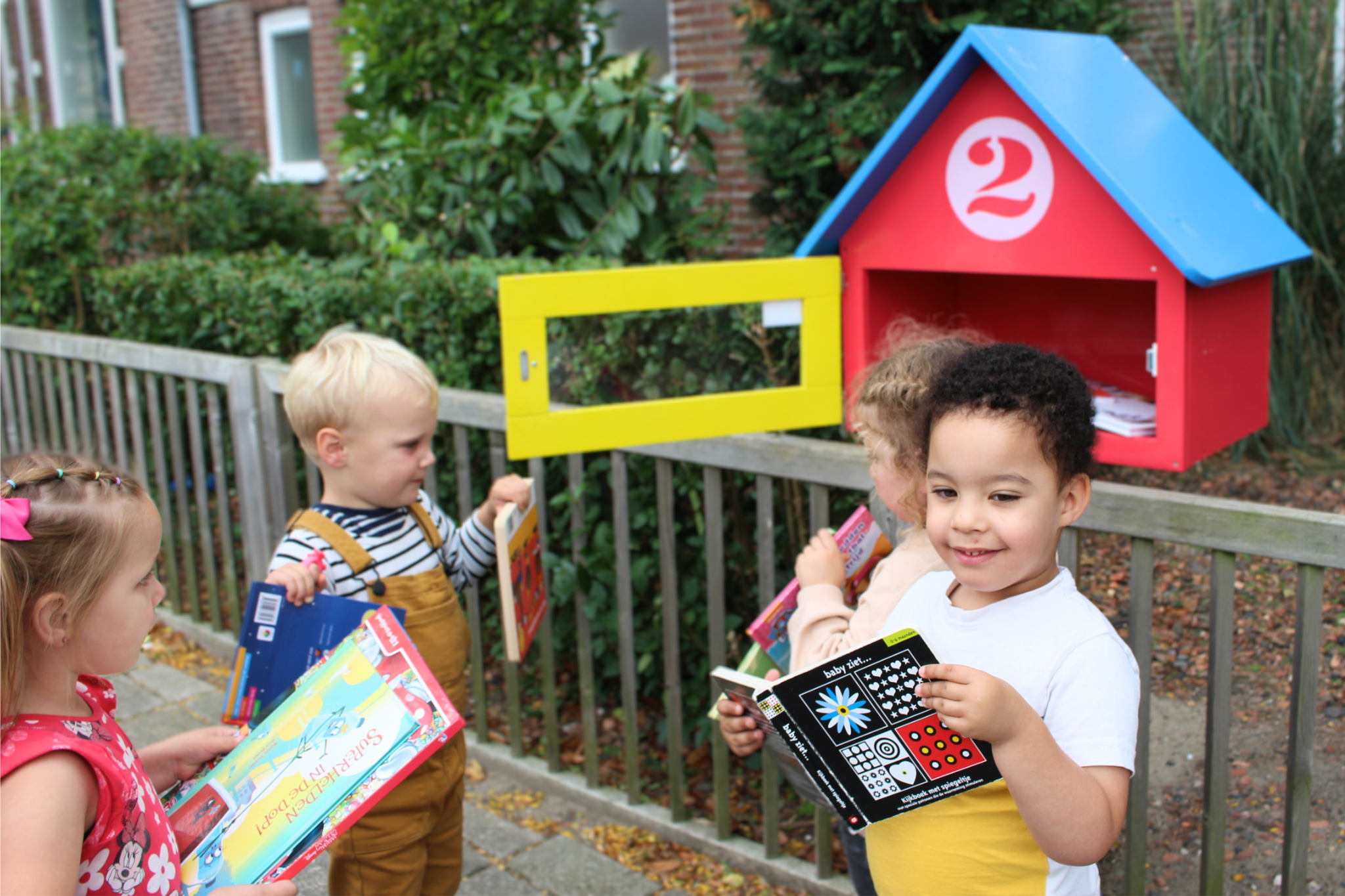 Kinderen lezen bij minibieb in de wijk