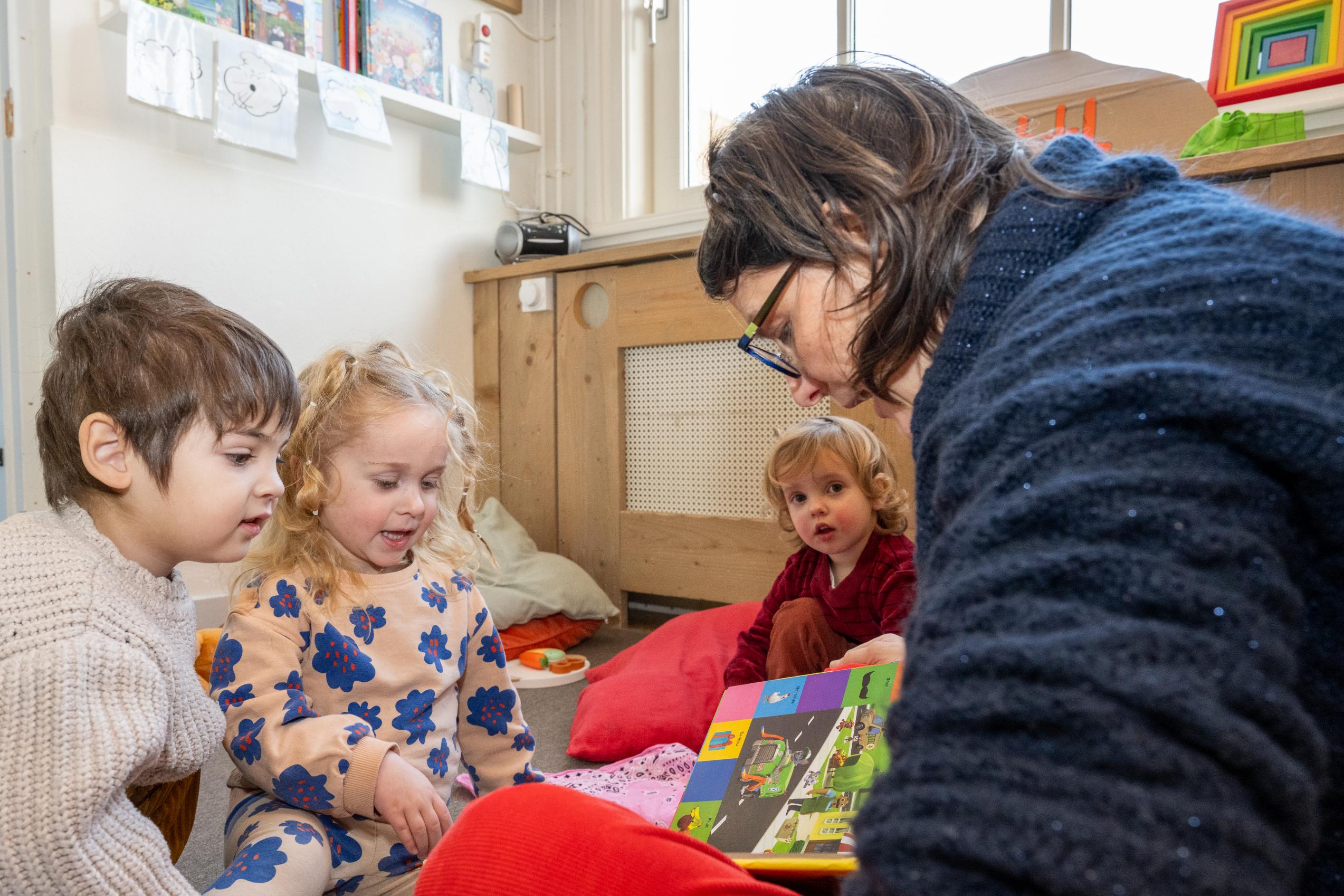 medewerker leest voor aan kinderen bij kinderdagverblijf 2koninkjes in centrum den haag