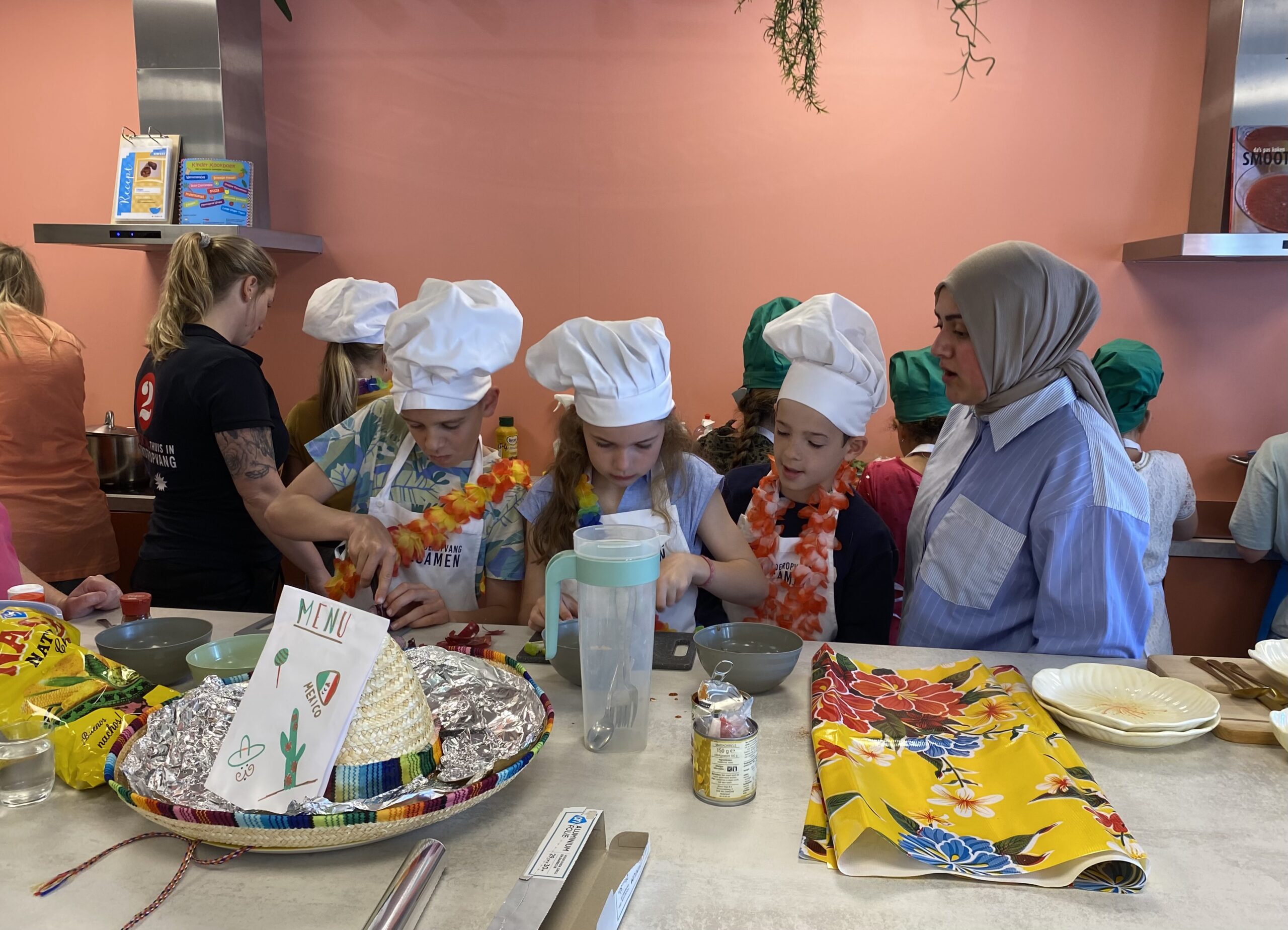 De kinderen zijn druk aan het koken en bereiden en de jury kijkt mee en stelt hen vragen. Meesterkoks 2024