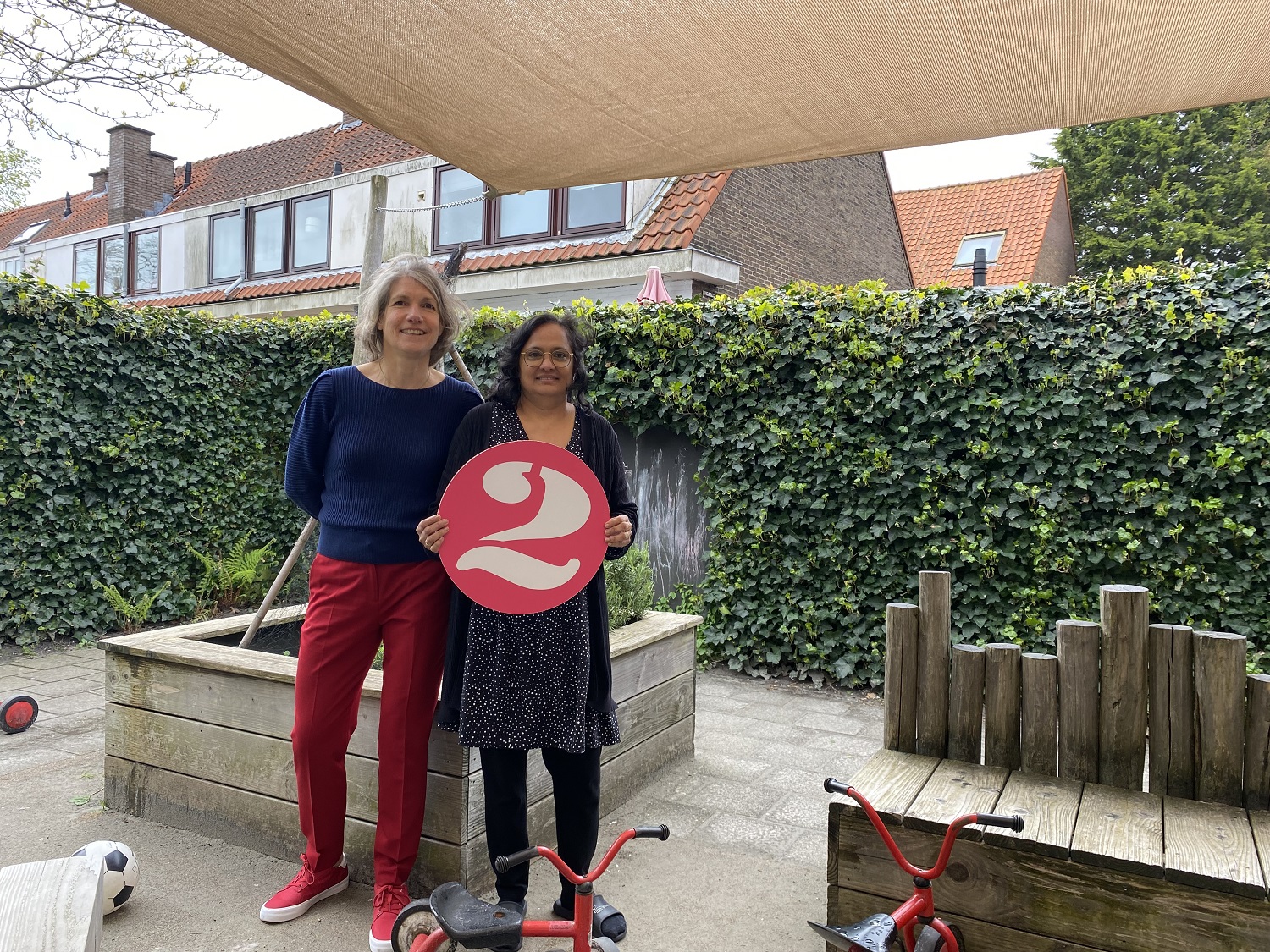 Taalles gratis met kinderopvang van 2Onder Elkaar. Asha pm en taaldocente Nicole staan in de afgeschermde speeltuin voor de peuters voorschoolse educatie